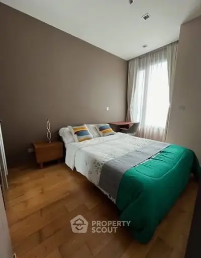 Cozy bedroom with wooden flooring and natural light from large window