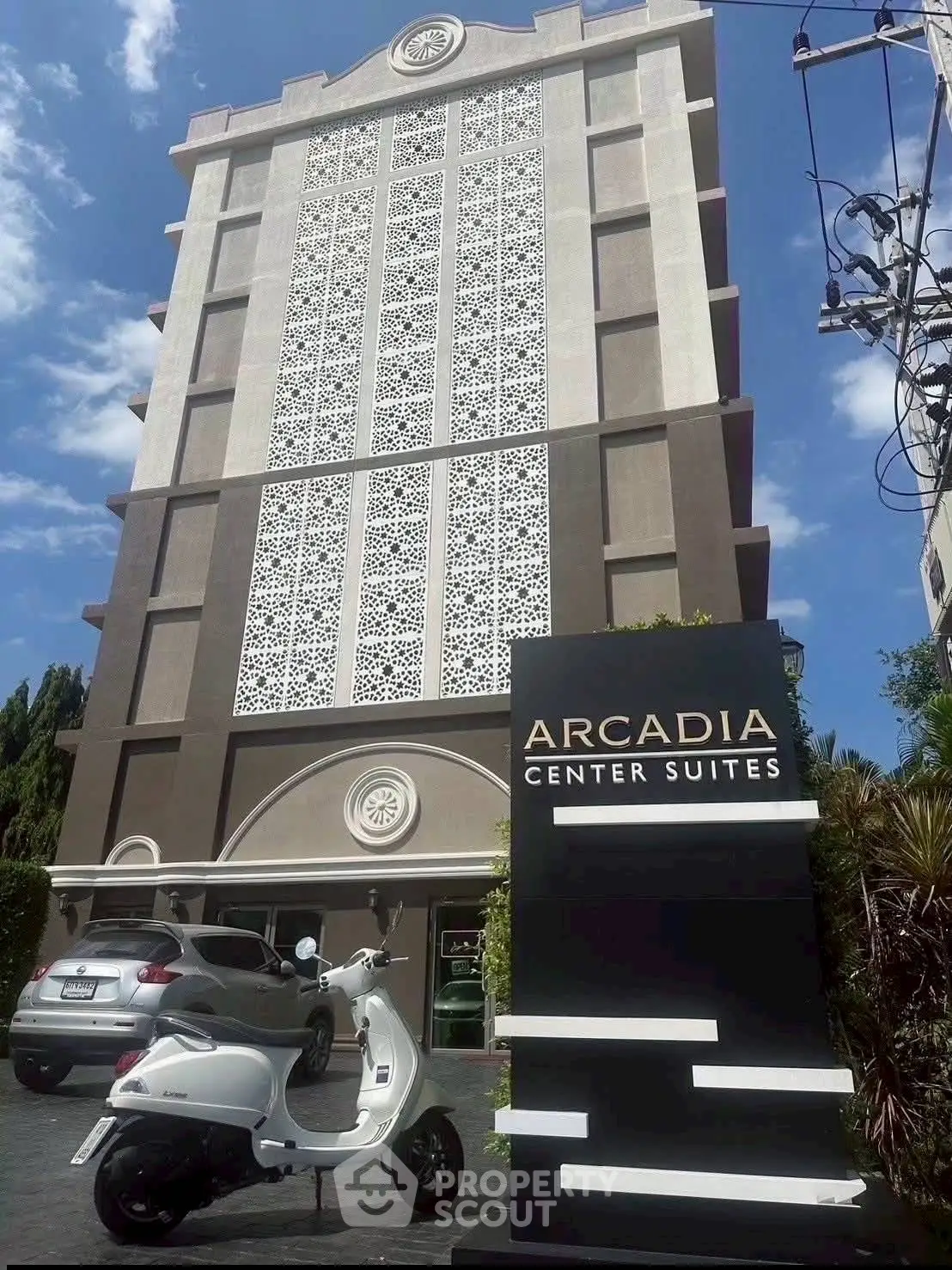 Modern building exterior of Arcadia Center Suites with stylish facade and parked scooter.
