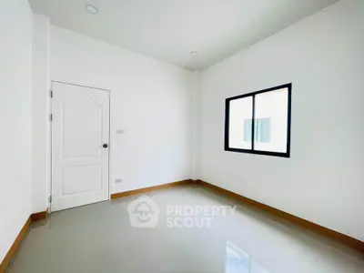 Spacious empty room with glossy tiled floor and large window, perfect for customization.