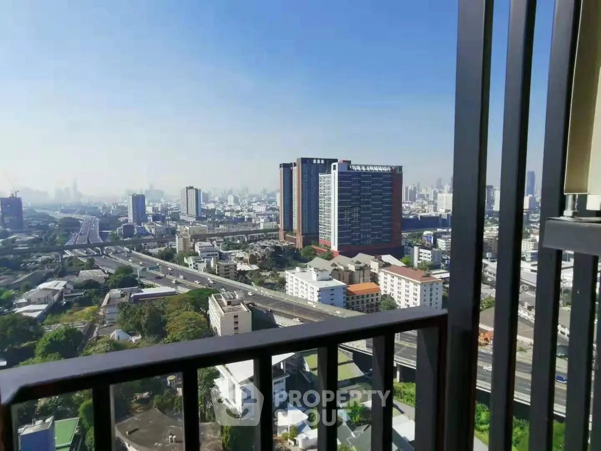 Stunning cityscape view from a high-rise balcony, showcasing urban skyline and clear blue skies.