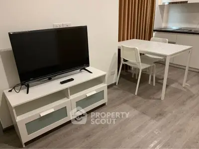 Modern apartment interior with sleek kitchen and cozy dining area, featuring a flat-screen TV and stylish furniture.