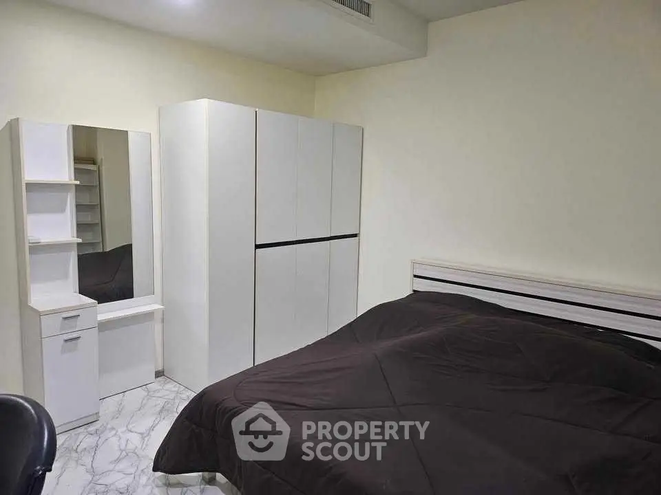 Modern bedroom with sleek white furniture and cozy bedding