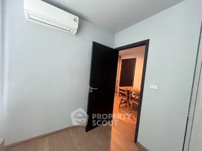 Modern interior with air conditioning and wooden flooring, open door to dining area.