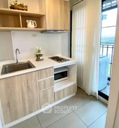 Modern compact kitchen with wooden cabinets and balcony view