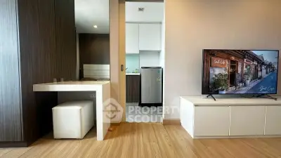 Modern apartment interior with stylish living room and kitchen area, featuring sleek furniture and wooden flooring.
