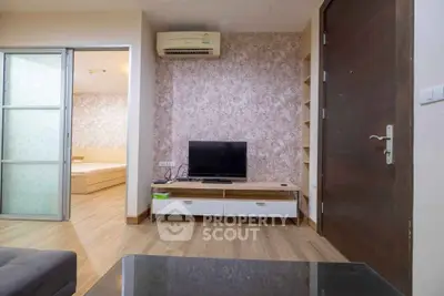 Modern living room with stylish decor and open view to bedroom, featuring sleek furniture and air conditioning.