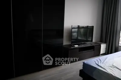 Modern bedroom with sleek black wardrobe and flat-screen TV, perfect for contemporary living.