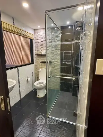 Modern bathroom with glass shower and stone accent wall