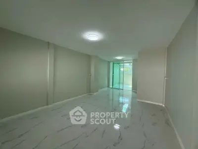 Spacious modern living room with sleek marble flooring and glass doors leading to a balcony.