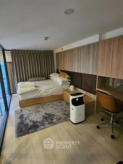 Modern bedroom with stylish decor, large windows, and cozy workspace in a high-rise apartment.
