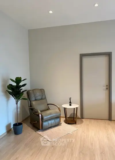 Minimalist interior with cozy armchair and plant, perfect for relaxation.