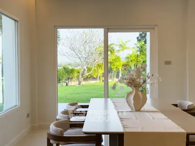 Elegant dining area with large windows overlooking lush garden view
