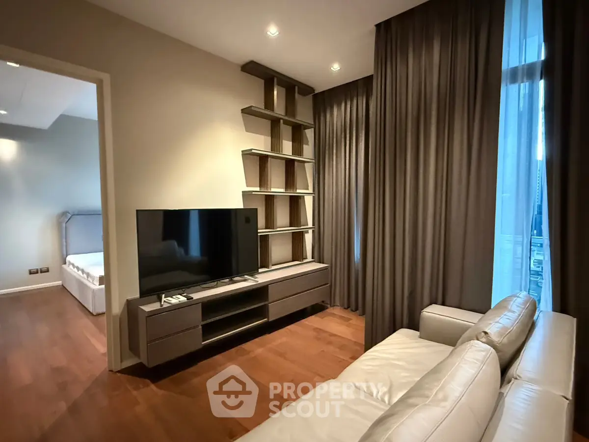 Modern living room with sleek TV unit and cozy sofa, adjacent to a stylish bedroom.
