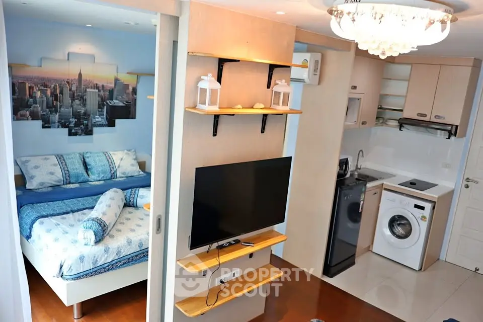 Modern studio apartment with open layout, featuring a cozy bedroom and compact kitchen with washing machine.