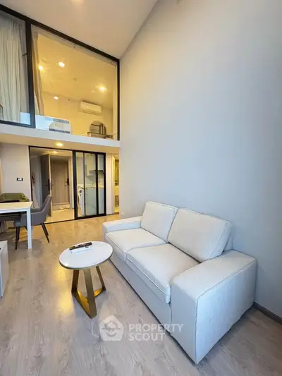Modern loft apartment with high ceilings and stylish furniture, featuring a cozy living area and mezzanine bedroom.