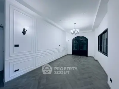 Elegant empty living room with classic wall paneling and chandelier lighting