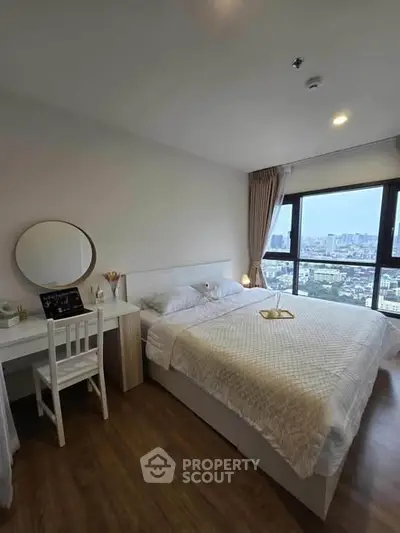 Modern bedroom with city view, featuring cozy bed and stylish workspace.