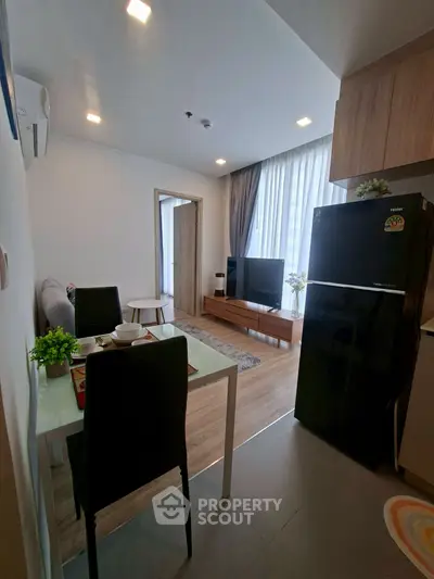 Modern open-plan living room with dining area and kitchen, featuring sleek furniture and natural light.