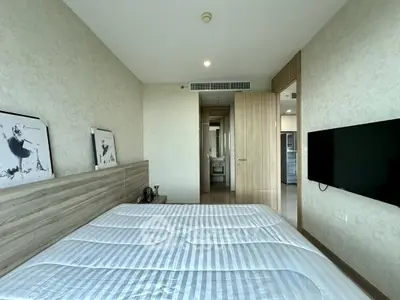 Modern bedroom with stylish decor and wall-mounted TV in a contemporary apartment.