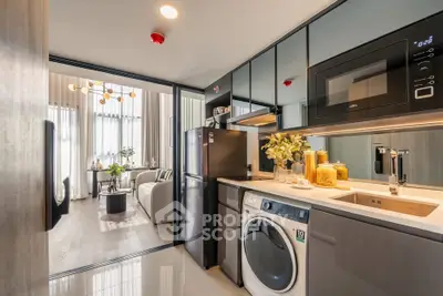 Modern kitchen with sleek appliances and open layout leading to a stylish living room.