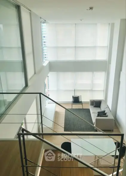 Modern two-story living room with large windows and minimalist decor.