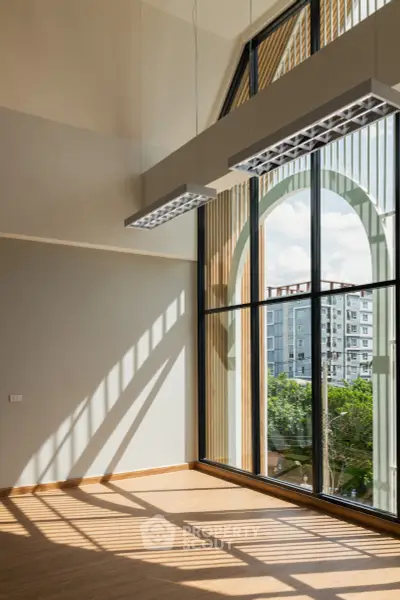 Spacious room with large arched windows offering stunning city views and abundant natural light.