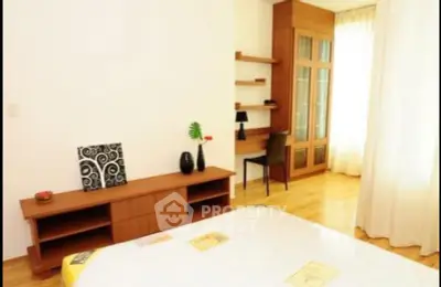 Spacious bedroom with wooden furniture and natural light, ideal for comfort and relaxation.