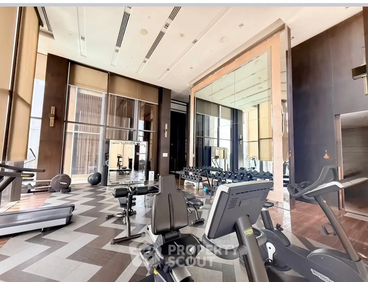 Luxurious gym with modern equipment and floor-to-ceiling windows in upscale building.
