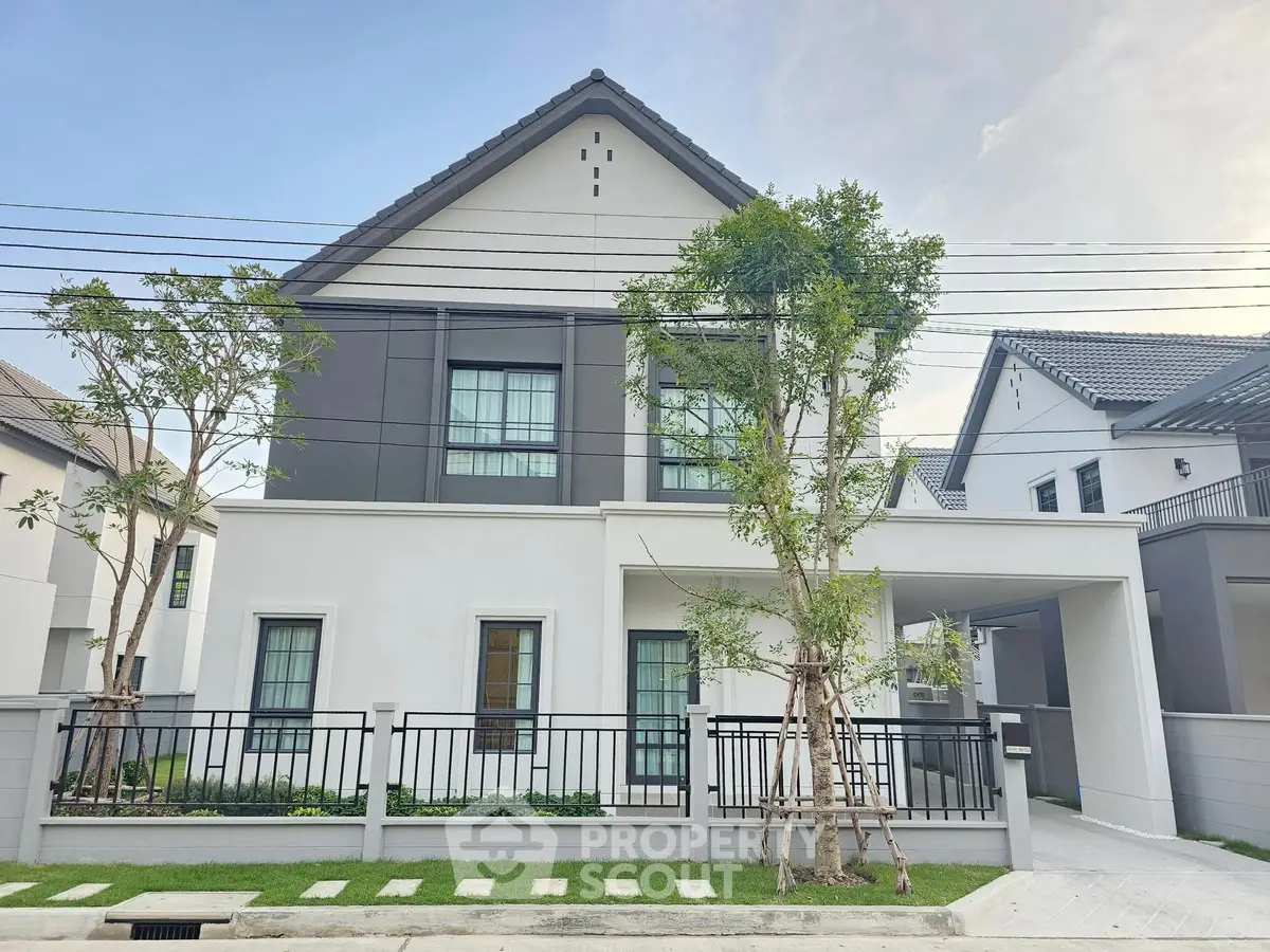 Modern two-story house with sleek design and landscaped front yard in a suburban neighborhood.
