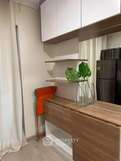 Modern kitchen with sleek cabinetry and stylish decor, featuring a compact fridge and elegant shelving.