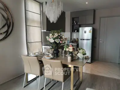 Elegant dining area with modern kitchen, featuring a chandelier and stylish decor.