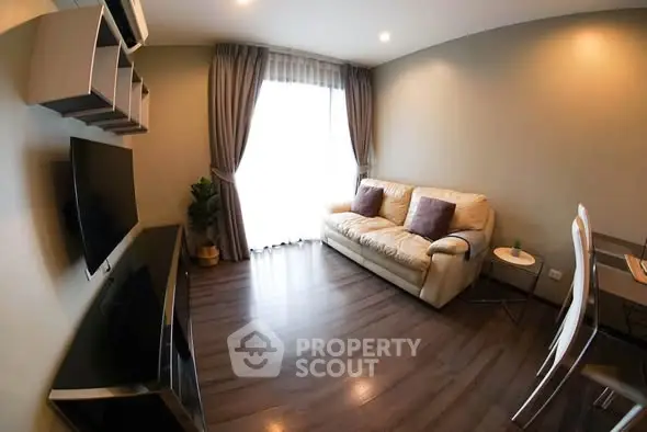 Cozy modern living room with hardwood floors, stylish sofa, and wall-mounted TV.