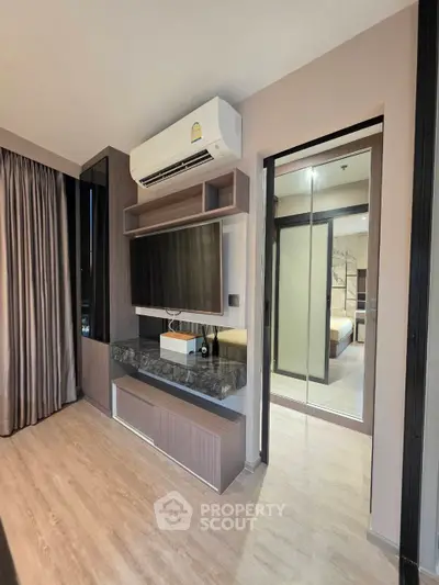 Modern living room with sleek TV setup and view into a stylish bedroom