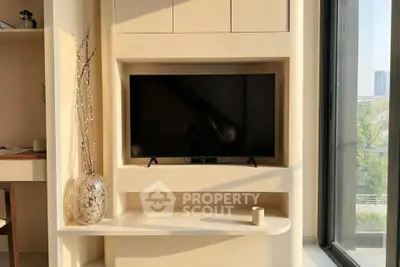 Modern living room with built-in TV unit and large window offering natural light.