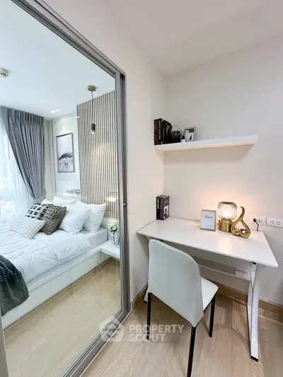Modern bedroom with study nook, featuring elegant decor and natural light.