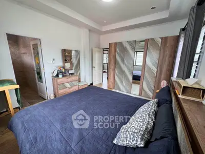 Spacious bedroom with modern decor and ensuite bathroom in a stylish home.