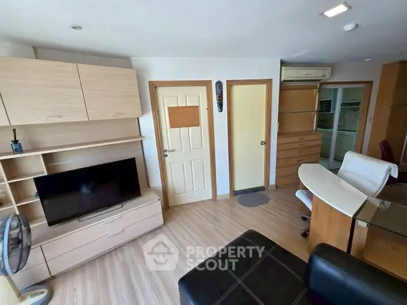 Modern living room with sleek furniture and TV, featuring light wood accents and open layout.