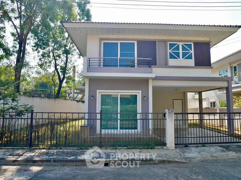 Modern two-story house with balcony and fenced yard in suburban neighborhood