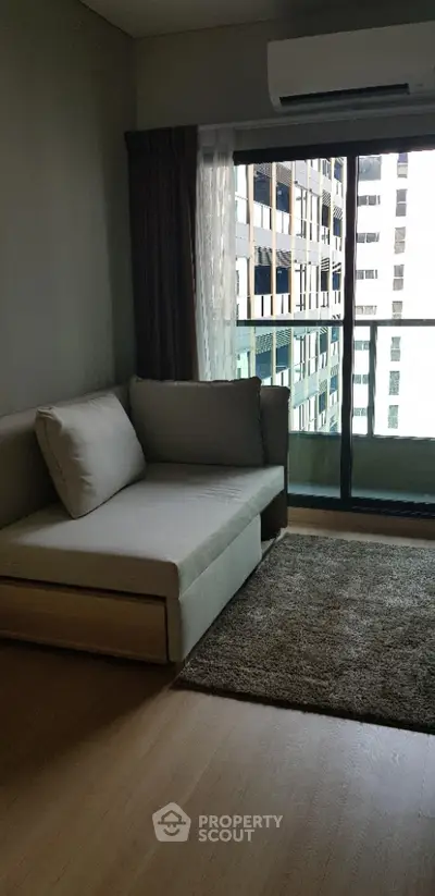 Modern living room with cozy sofa and city view balcony in a high-rise apartment.