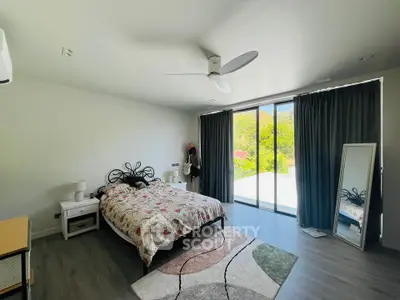 Spacious bedroom with large windows and modern decor, offering a serene view and ample natural light.
