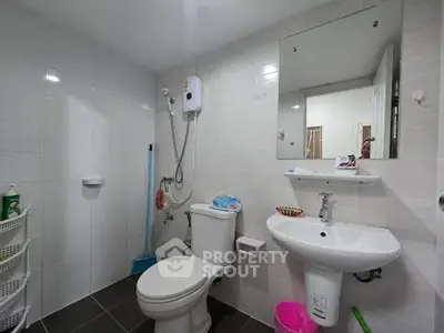 Modern bathroom with white tiles, shower, and sleek fixtures in a contemporary home.