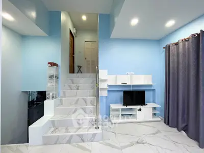 Modern living room with sleek staircase and stylish TV unit in a bright, airy space.