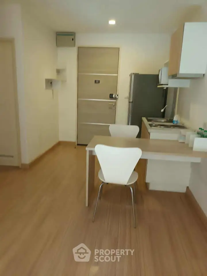 Modern compact kitchen with dining area in a cozy apartment, featuring sleek appliances and minimalist design.