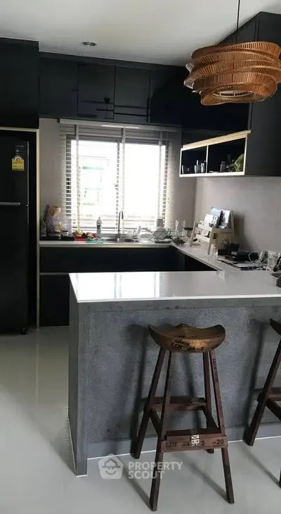 Modern kitchen with sleek black cabinets and a stylish island with wooden stools.