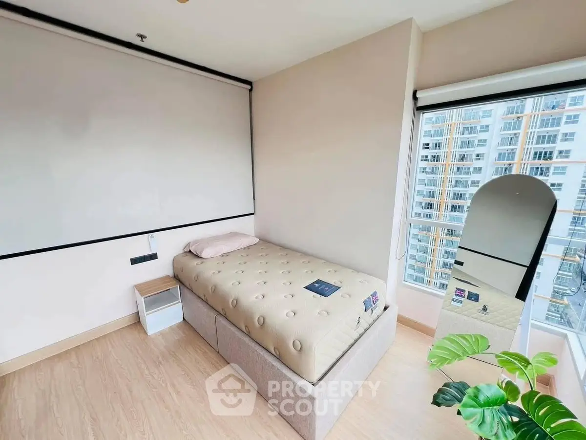 Modern bedroom with single bed and large window offering city view