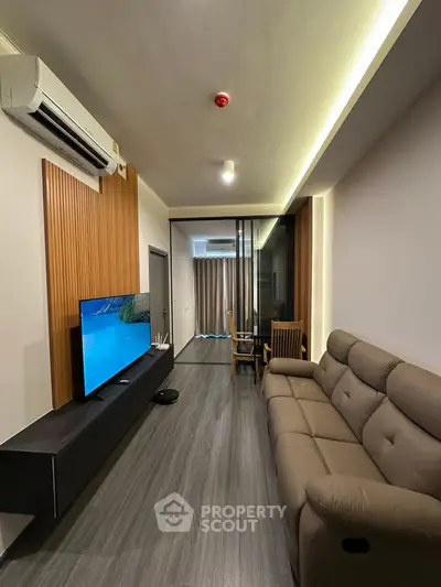 Modern living room with sleek design, featuring a comfortable sofa, wall-mounted TV, and stylish wood paneling.