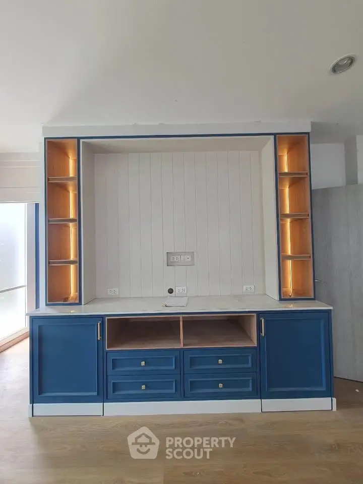 Modern blue built-in entertainment unit with open shelves and storage drawers in a stylish living room.