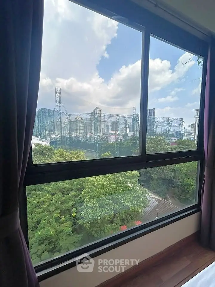 Stunning cityscape view from a modern apartment window, showcasing lush greenery and urban skyline.