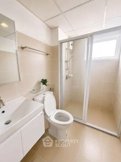 Modern bathroom with sleek fixtures and glass shower enclosure in a bright, neutral-toned design.