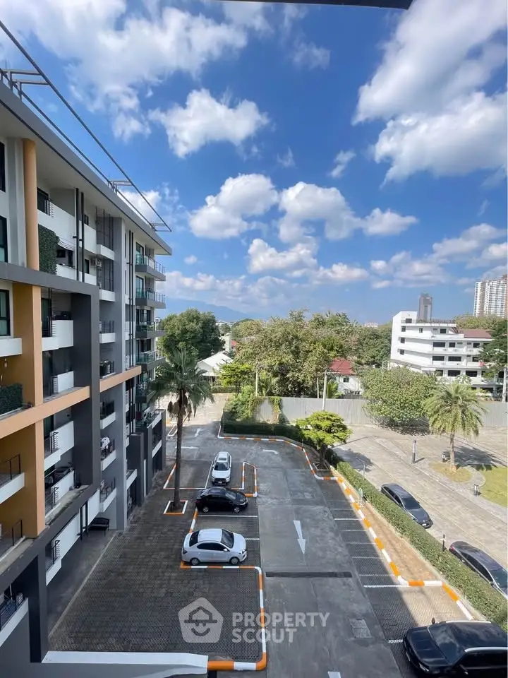 Modern apartment building with parking and scenic view under blue sky